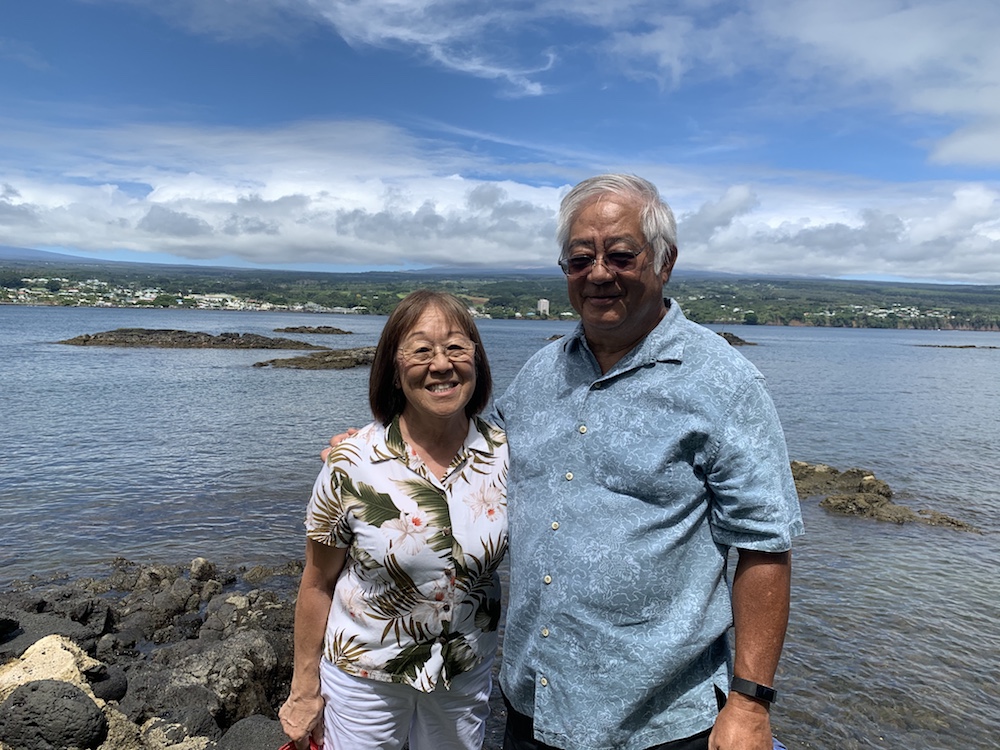 Couple posing along coast in Hawaii