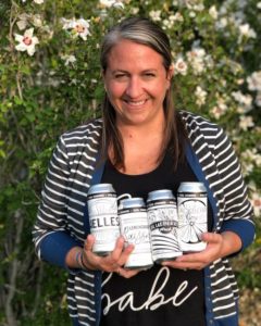 Megan Larson holding four beer cans with labels she designed