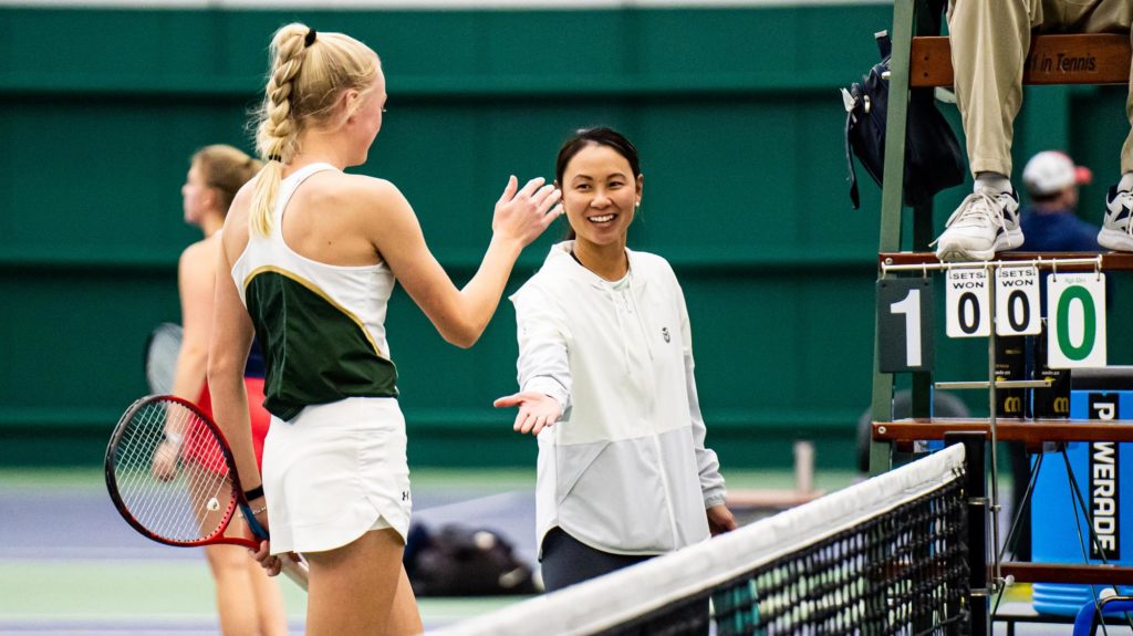 Tennis Coach Mai-Ly Tran gives a player a high five during a match. 