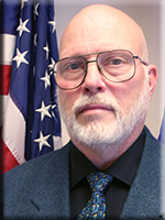 Headshot of Bill Morrow with US flag in background