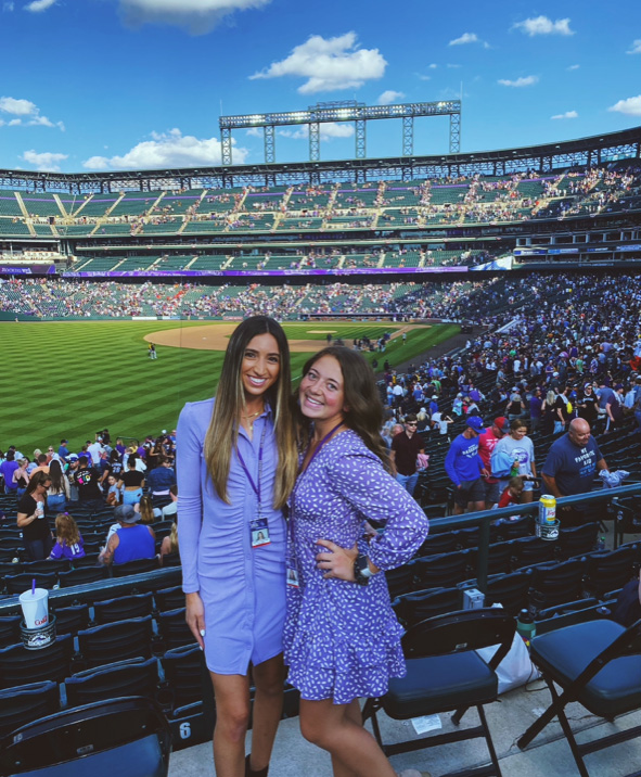 Katie George standing in the stands of Coors Field with a coworker. 
