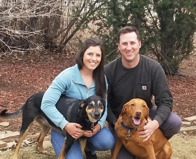 Beau Brittenham with his wife and two dogs in front of some trees