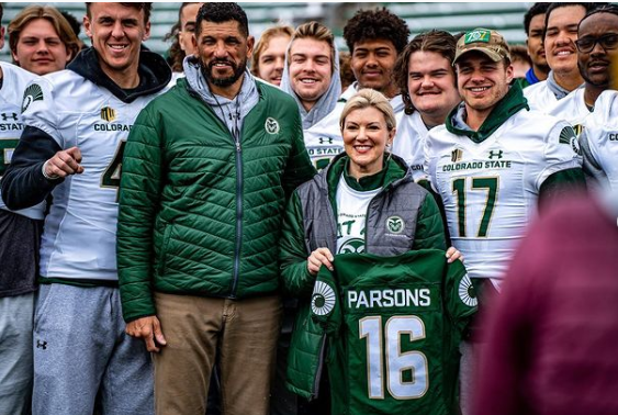 President Parsons shows her new CSU Rams jersey while standing beside Coach Jay Norvell.