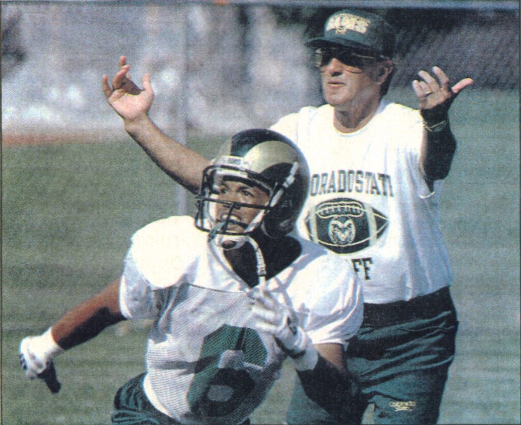 Ronald Antoine practices as Coach Sonny Lubick coaches in the background. 