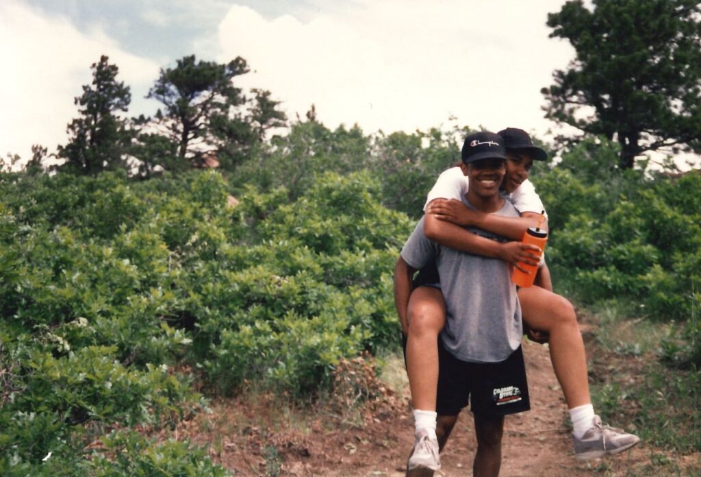 Ronald Antoine carries Zenarae on his back while hiking a trail. 
