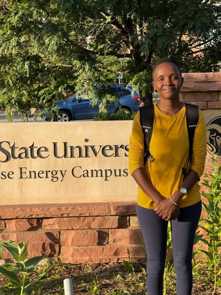 Fancy Cheptonui standing in front of the CSU's Energy Institute sign. 