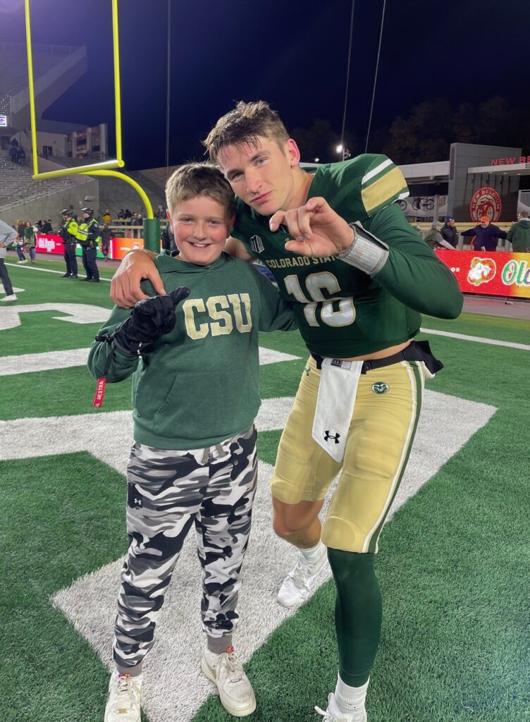 Kathleen Pitre's son poses with Rams quarterback Brayden Fowler-Nicolosi on the field at Canvas Stadium. 